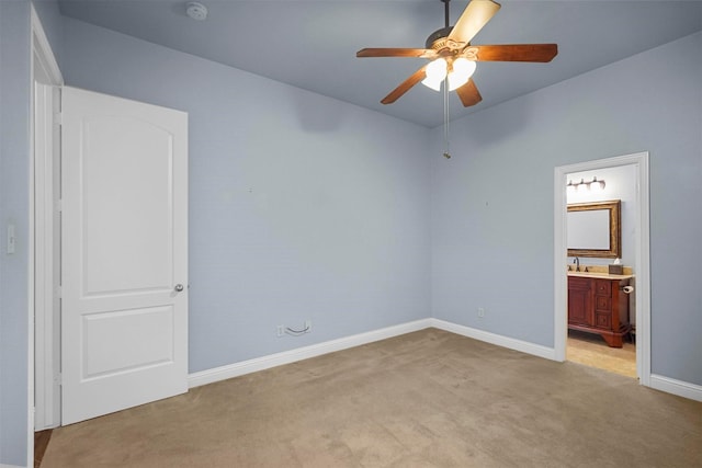 unfurnished bedroom with light carpet, baseboards, connected bathroom, and a sink