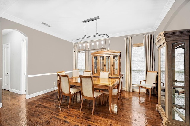 dining room featuring visible vents, baseboards, ornamental molding, dark wood finished floors, and arched walkways