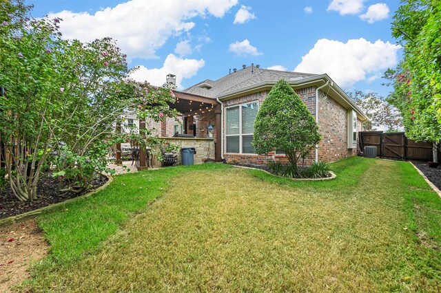 rear view of house featuring a patio, brick siding, a gate, and a yard