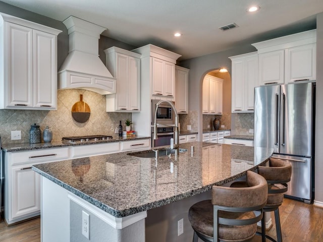 3009 Morning Star Dr, Little Elm, TX 75068 - kitchen with stainless steel appliances, wood finished floors, visible vents, an island with sink, and custom range hood