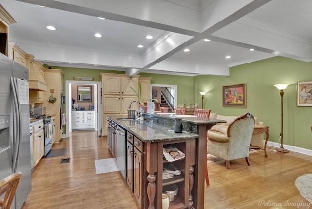 kitchen with ornamental molding, a breakfast bar, a large island, appliances with stainless steel finishes, and baseboards