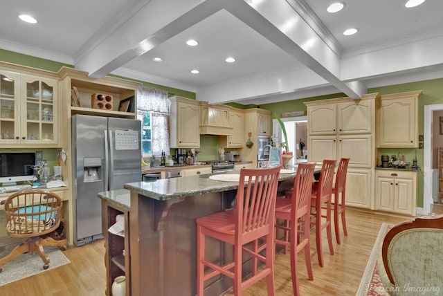 kitchen with ornamental molding, appliances with stainless steel finishes, beamed ceiling, light wood-style flooring, and cream cabinets