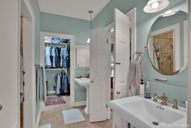 bathroom with a spacious closet, a shower stall, a sink, and crown molding