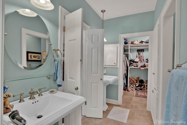 bathroom with a sink, a spacious closet, and crown molding