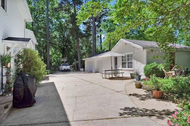 view of home's exterior featuring concrete driveway, a patio area, an outdoor structure, and an attached garage