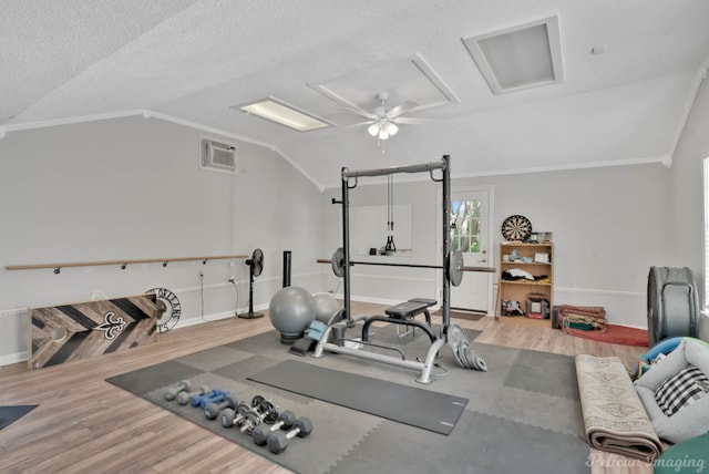 exercise room featuring wood finished floors, attic access, and vaulted ceiling