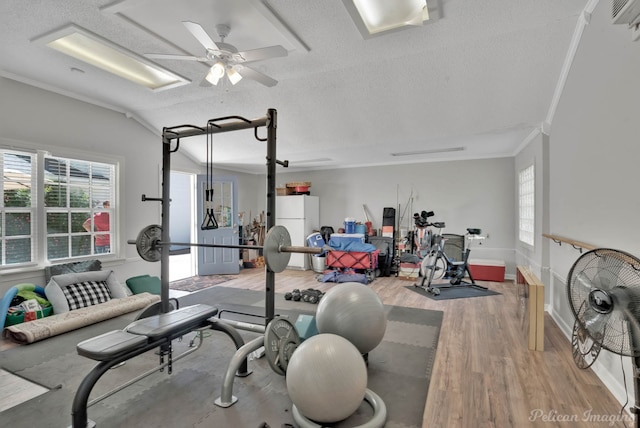 exercise room with a textured ceiling, wood finished floors, crown molding, and a ceiling fan