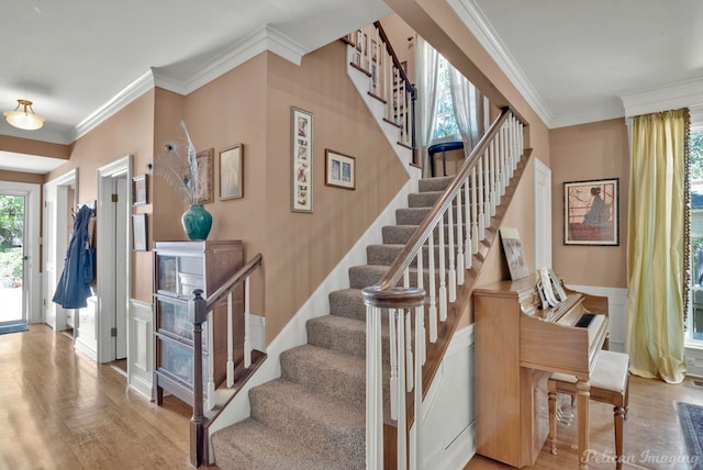 staircase featuring ornamental molding, a wainscoted wall, and wood finished floors