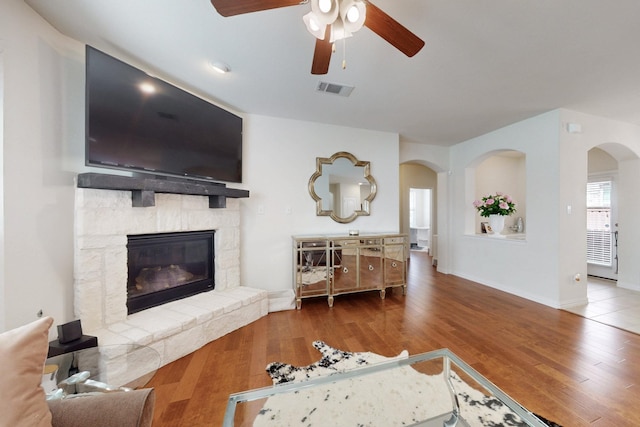 2037 Barx Dr, Little Elm, TX 75068 - living area with arched walkways, a ceiling fan, wood finished floors, and a fireplace
