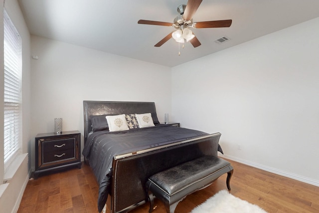 bedroom featuring wood finished floors, visible vents, baseboards, and ceiling fan