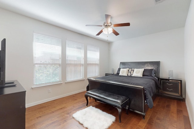 bedroom featuring baseboards, wood finished floors, and multiple windows