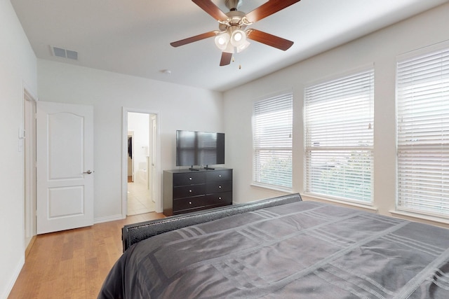 bedroom featuring baseboards, visible vents, a ceiling fan, wood finished floors, and connected bathroom