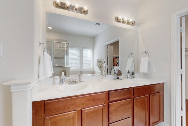 full bath with visible vents, a sink, a shower stall, and double vanity