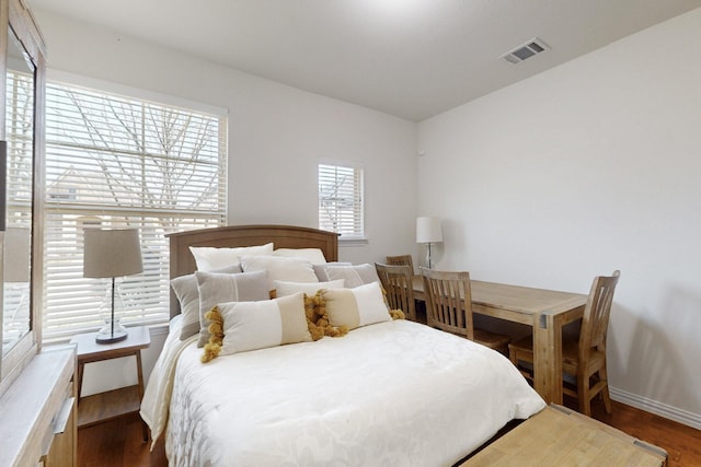 bedroom featuring baseboards, wood finished floors, and visible vents