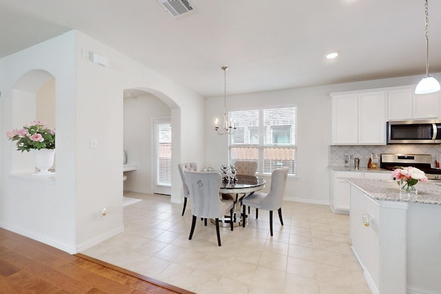 dining room featuring arched walkways, baseboards, a notable chandelier, visible vents, and recessed lighting