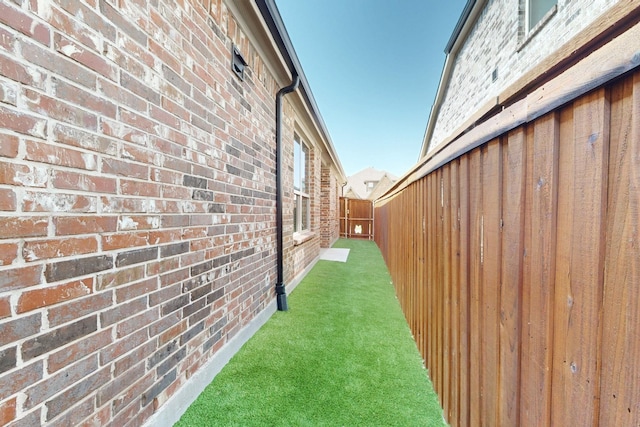 view of side of property with brick siding, a yard, and fence