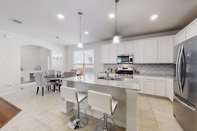kitchen featuring stainless steel appliances, a sink, tasteful backsplash, visible vents, and light tile patterned floors