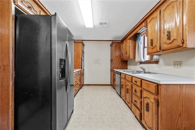kitchen featuring a sink, brown cabinetry, light countertops, and appliances with stainless steel finishes