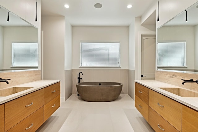 137 Ambrosia Ln, Heath, TX 75032 - bathroom with two vanities, a freestanding bath, plenty of natural light, wainscoting, and recessed lighting
