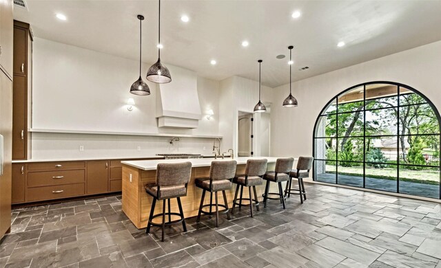 137 Ambrosia Ln, Heath, TX 75032 - kitchen with light countertops, a large island with sink, a kitchen bar, recessed lighting, and pendant lighting