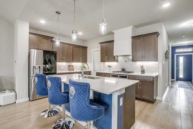 10600 Barrington Ln, Fort Worth, TX 76126 - kitchen featuring a kitchen bar, stainless steel refrigerator with ice dispenser, light countertops, a sink, and light wood finished floors