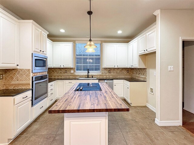 kitchen featuring white cabinets, butcher block counters, stainless steel appliances, backsplash, and ornamental molding