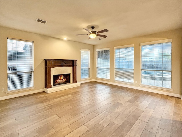 unfurnished living room with a ceiling fan, visible vents, wood finished floors, and a fireplace