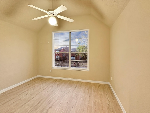 spare room featuring lofted ceiling, a ceiling fan, light wood-style floors, and baseboards