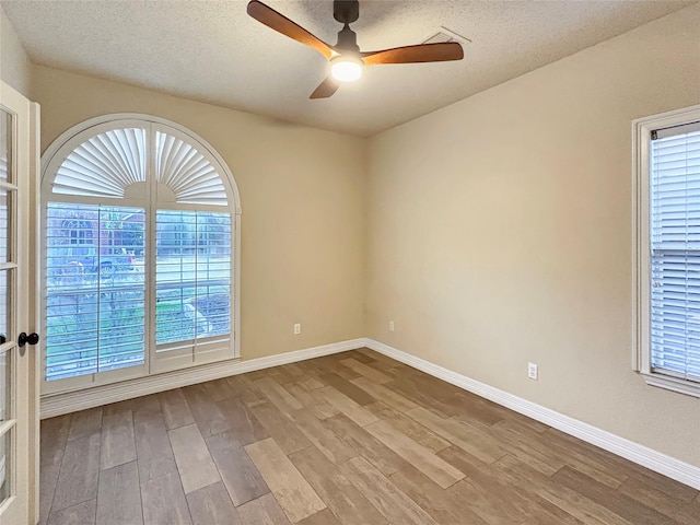 unfurnished room featuring baseboards, a ceiling fan, wood finished floors, and a textured ceiling
