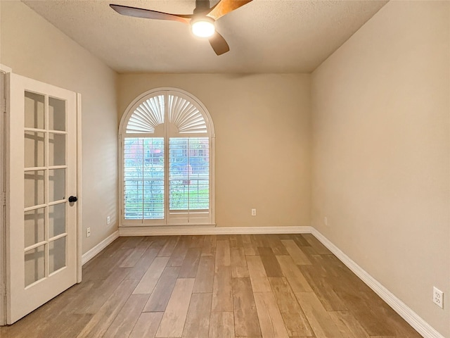 unfurnished room featuring baseboards, a ceiling fan, wood finished floors, and a textured ceiling