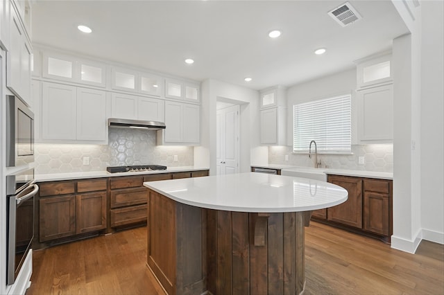2836 Holland Ct, Celina, TX 75009 - kitchen with glass insert cabinets, a sink, appliances with stainless steel finishes, light countertops, and light wood finished floors