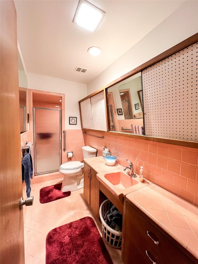 220 N 15th Ave, Munday, TX 76371 - full bathroom with vanity, tile walls, toilet, a shower stall, and visible vents