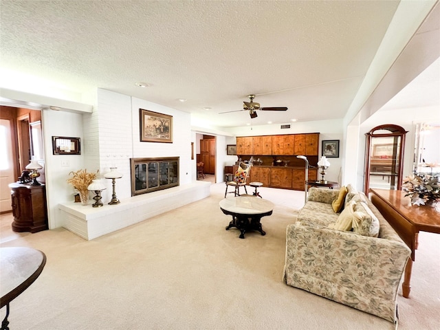 220 N 15th Ave, Munday, TX 76371 - living room with a ceiling fan, a glass covered fireplace, a textured ceiling, light colored carpet, and visible vents