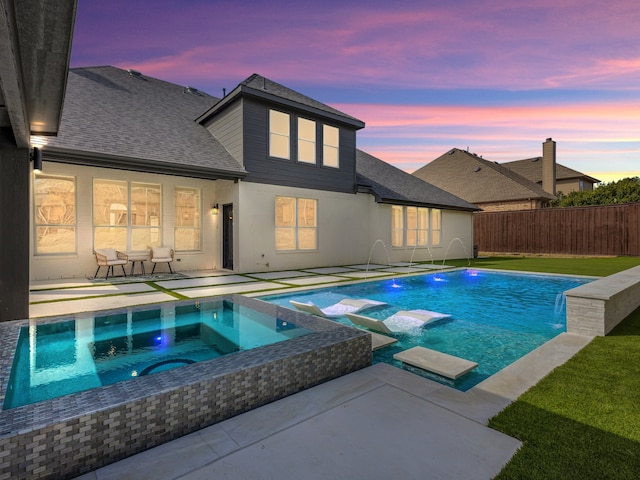 view of pool with a patio area, a pool with connected hot tub, and fence