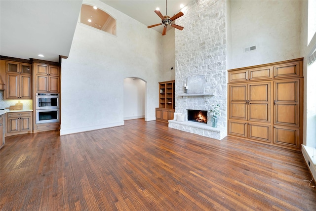 5460 Stone Canyon Dr, Frisco, TX 75034 - unfurnished living room featuring a ceiling fan, a high ceiling, visible vents, arched walkways, and dark wood-style floors