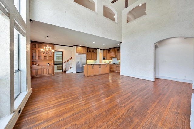 5460 Stone Canyon Dr, Frisco, TX 75034 - unfurnished living room with ceiling fan with notable chandelier, dark wood-type flooring, a towering ceiling, arched walkways, and stairs