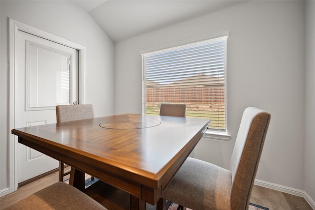 dining room featuring baseboards, vaulted ceiling, and wood finished floors