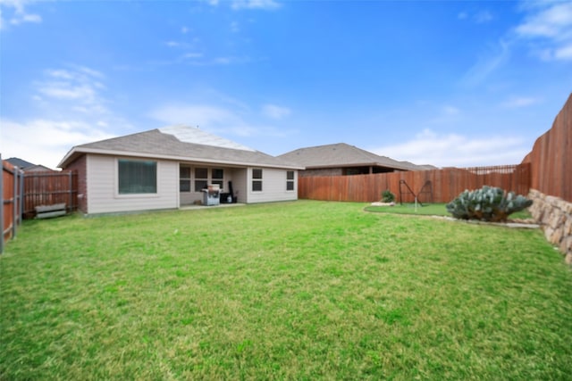 back of house with a fenced backyard and a lawn