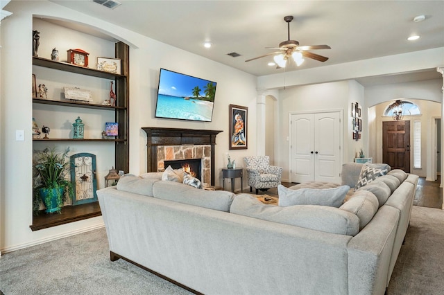 5218 Pueblo Ln, Frisco, TX 75034 - living room with arched walkways, carpet flooring, a ceiling fan, a stone fireplace, and recessed lighting
