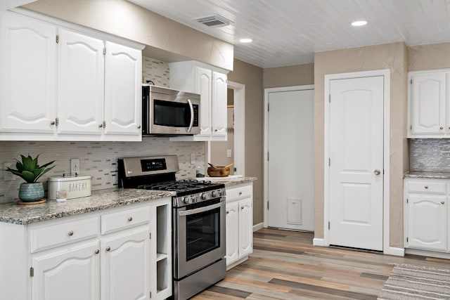 kitchen featuring white cabinetry, light wood-type flooring, backsplash, light stone counters, and appliances with stainless steel finishes