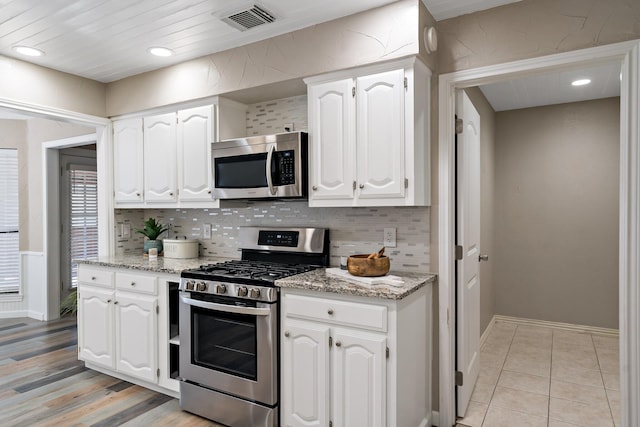 kitchen with visible vents, white cabinets, decorative backsplash, and appliances with stainless steel finishes
