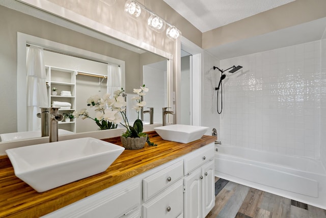 full bath featuring double vanity, a sink, washtub / shower combination, and wood finished floors