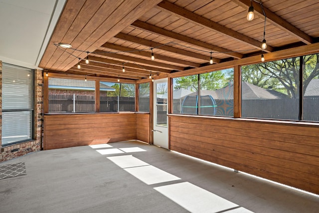 unfurnished sunroom featuring plenty of natural light, beamed ceiling, and track lighting