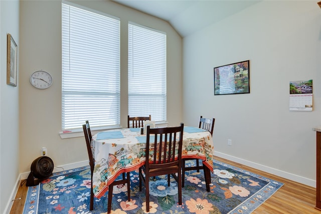 dining room featuring baseboards, wood finished floors, and vaulted ceiling