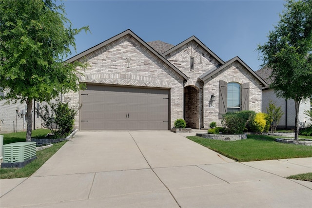 french country style house featuring brick siding, concrete driveway, a front yard, and an attached garage