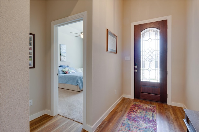 entrance foyer featuring ceiling fan, baseboards, wood finished floors, and plenty of natural light