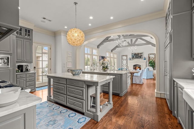 kitchen featuring gray cabinetry, arched walkways, an inviting chandelier, and a center island