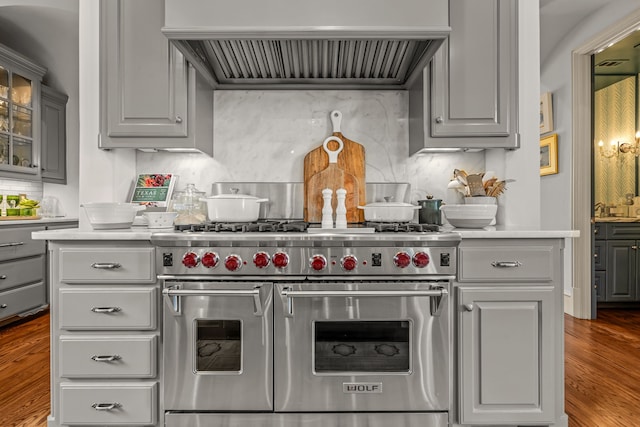 kitchen featuring double oven range, light countertops, wood finished floors, and premium range hood
