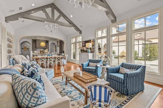 living area with light wood-style flooring, a wealth of natural light, arched walkways, and a chandelier