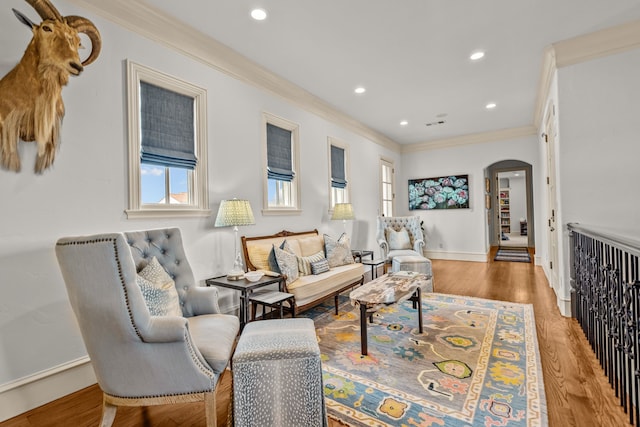 living area with recessed lighting, ornamental molding, baseboards, arched walkways, and wood finished floors